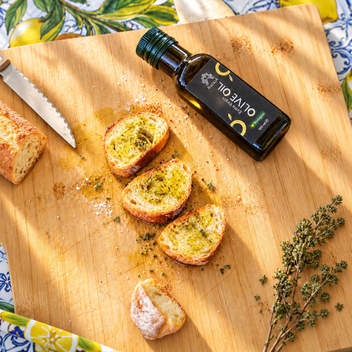 Bruschettas assaisonnées d'huile d'olive bio Racilia 100 ml sur une planche en bois